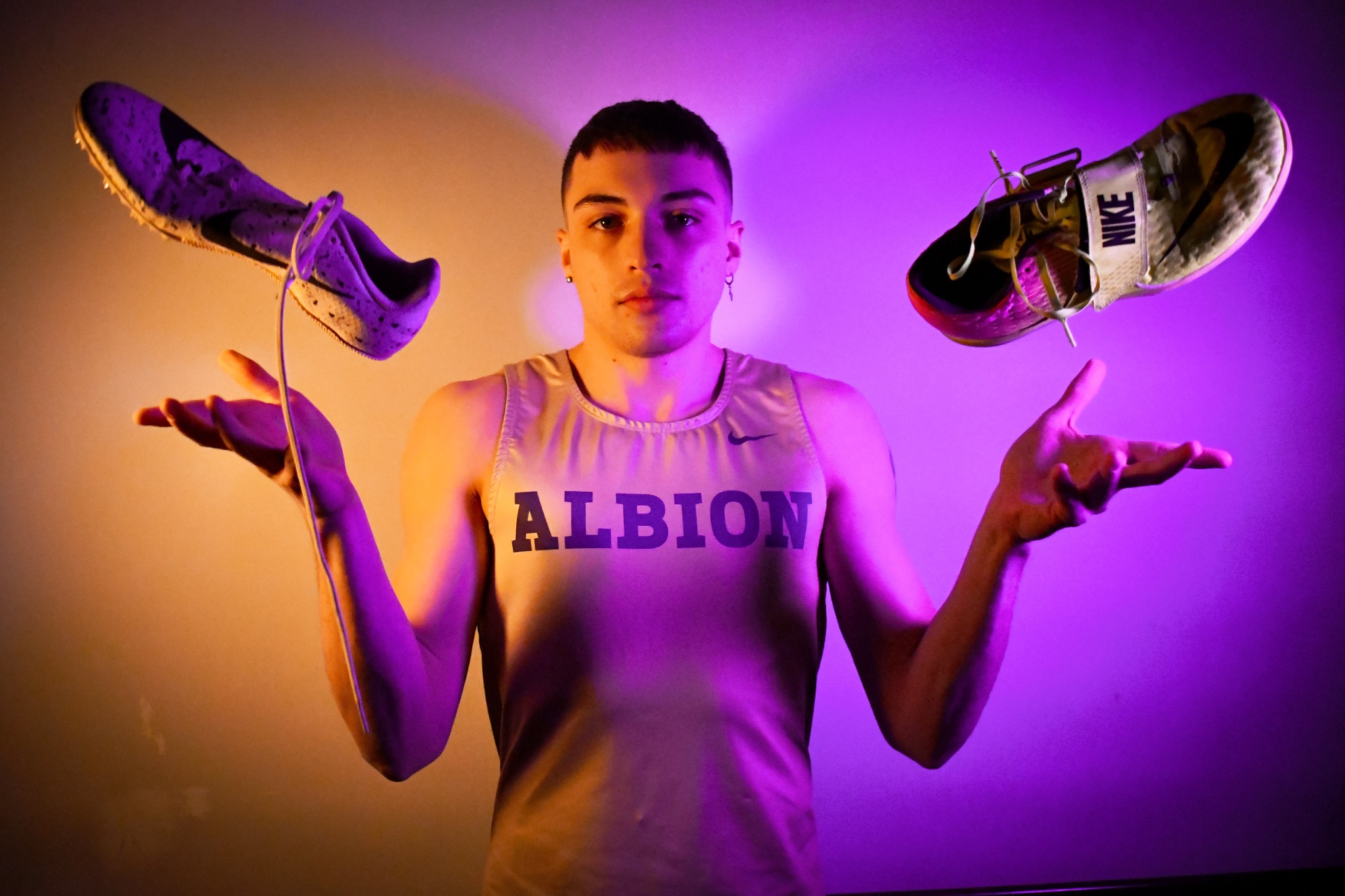 Albion athlete portrait with track shoes suspended above both hands