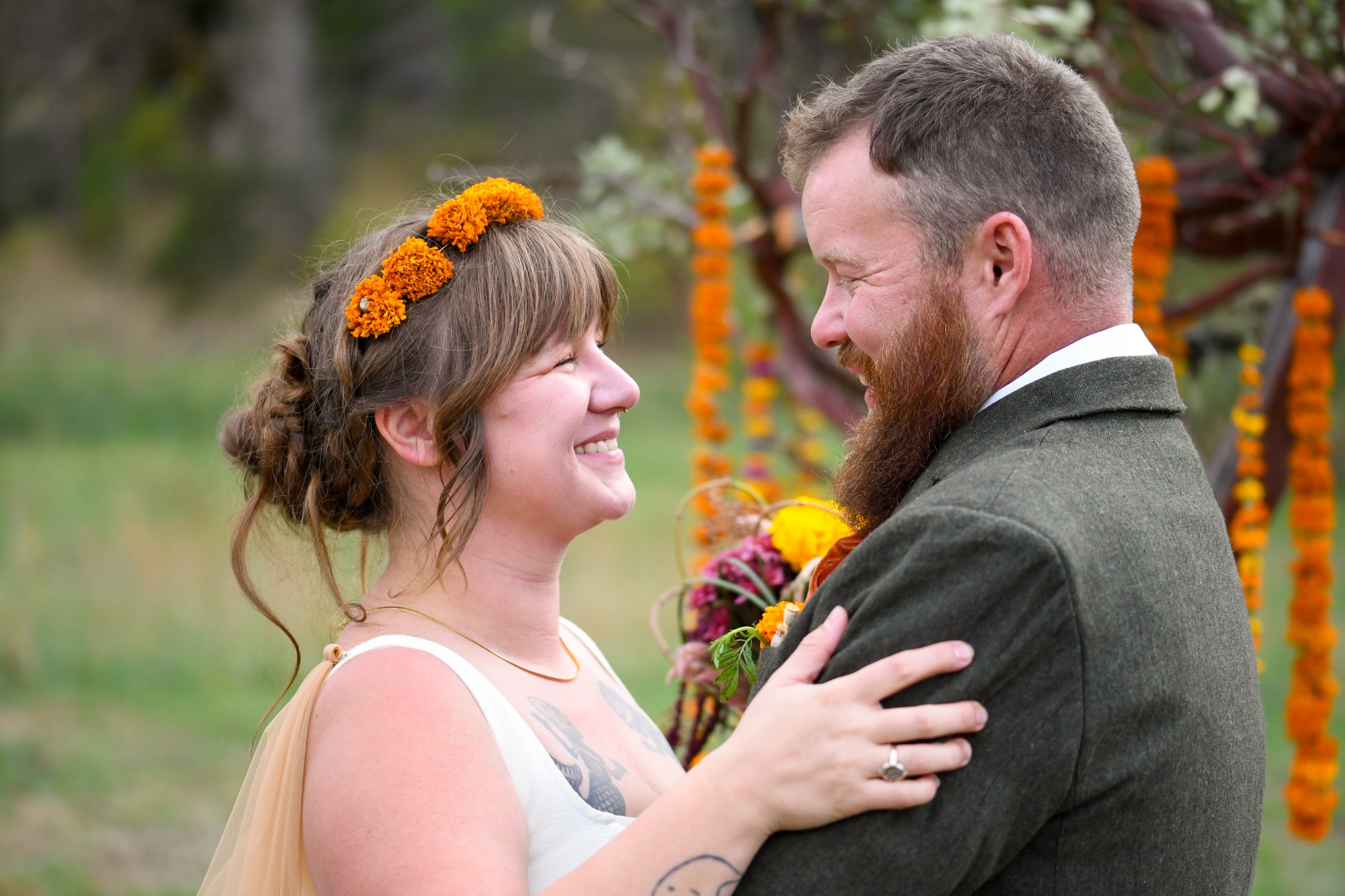 Wedding couple smiling at one another during an outdoor ceremony