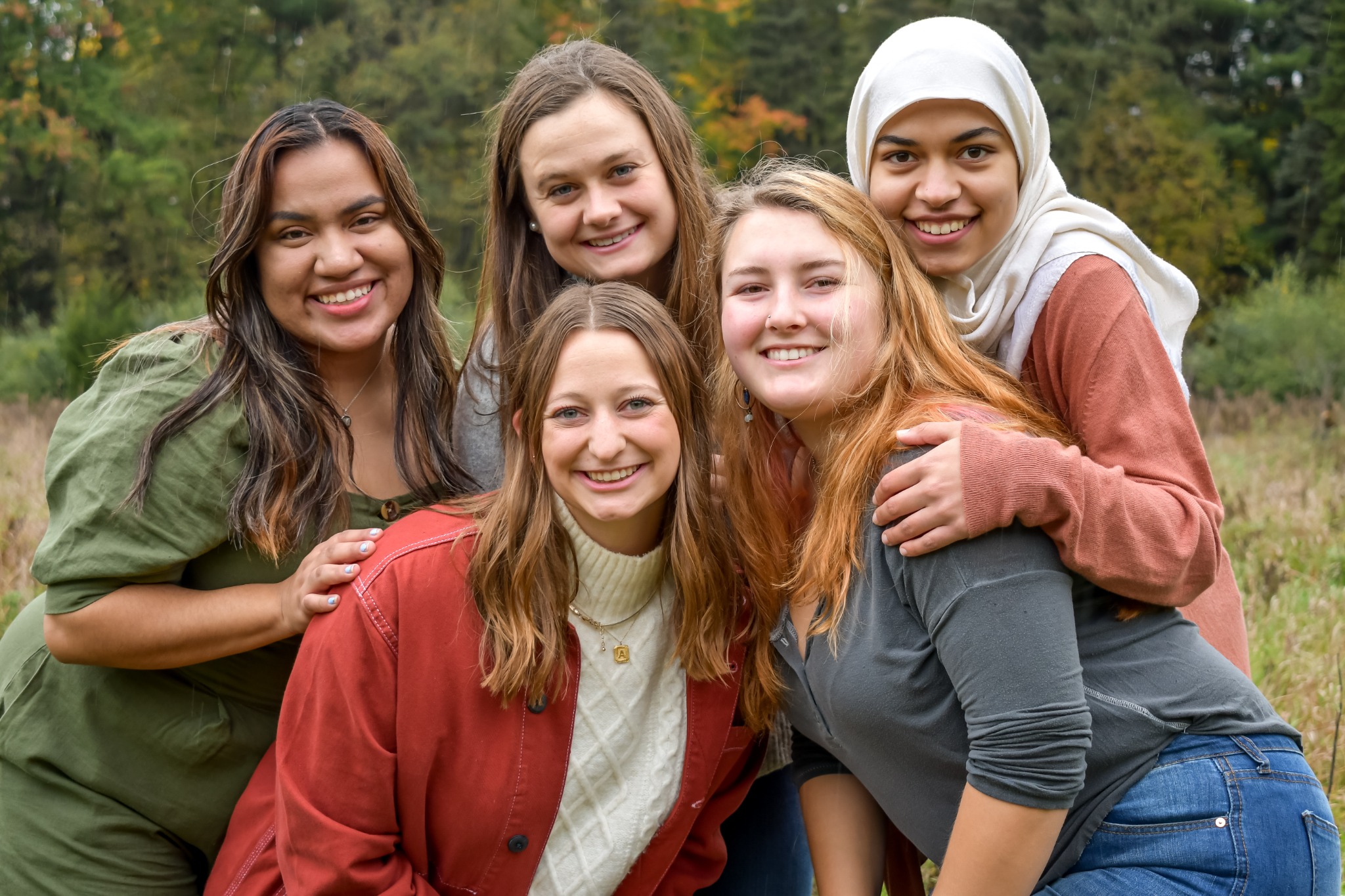 Five friends gathered together outdoors in a field