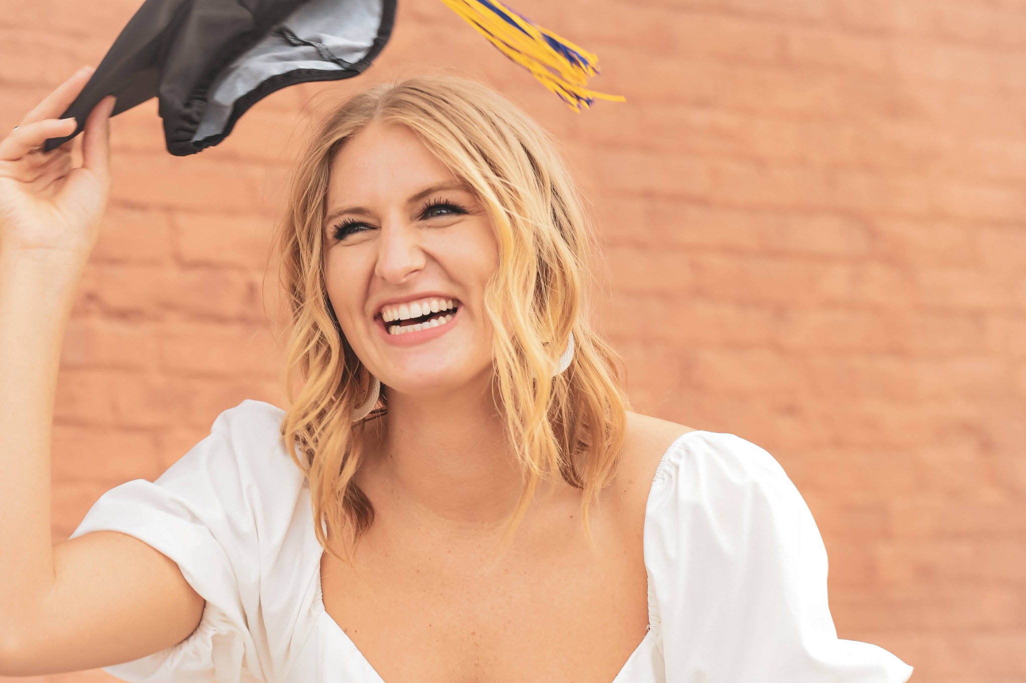 Graduate laughing while lifting her cap