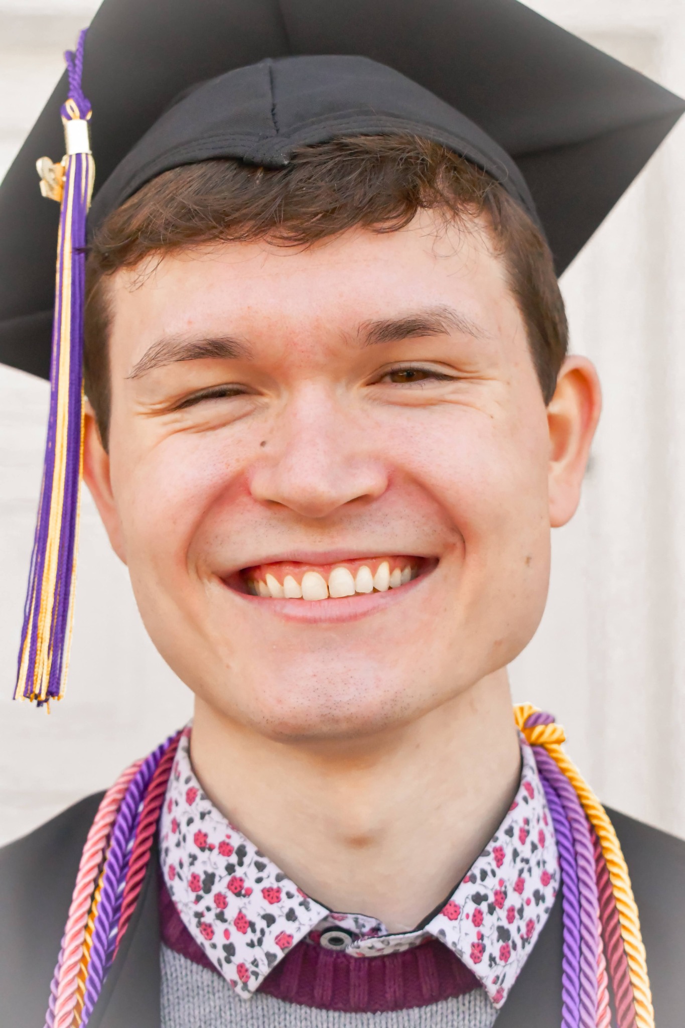 Albion graduate smiling in cap and honor cords