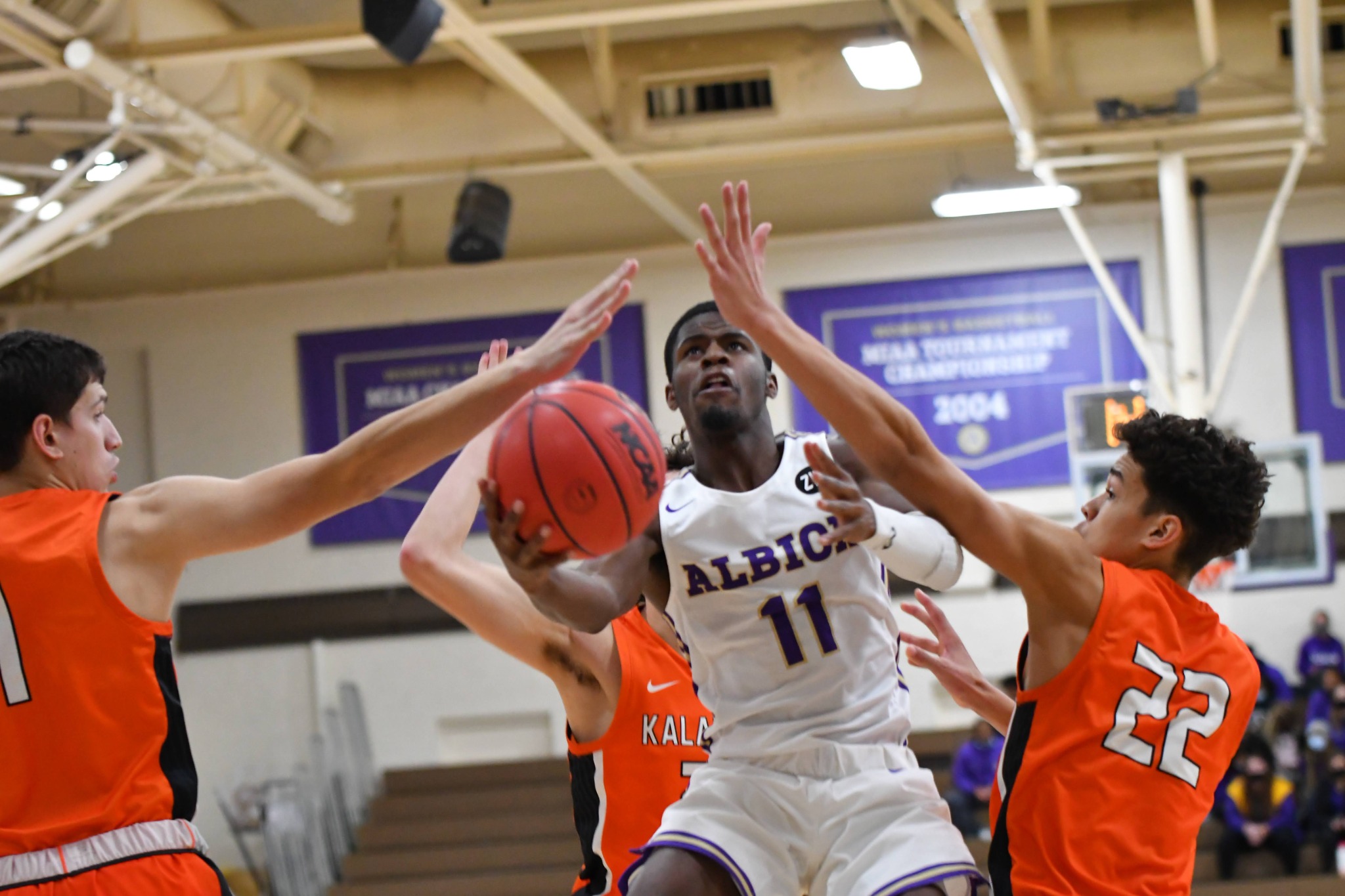 Albion basketball player driving through defenders toward the basket