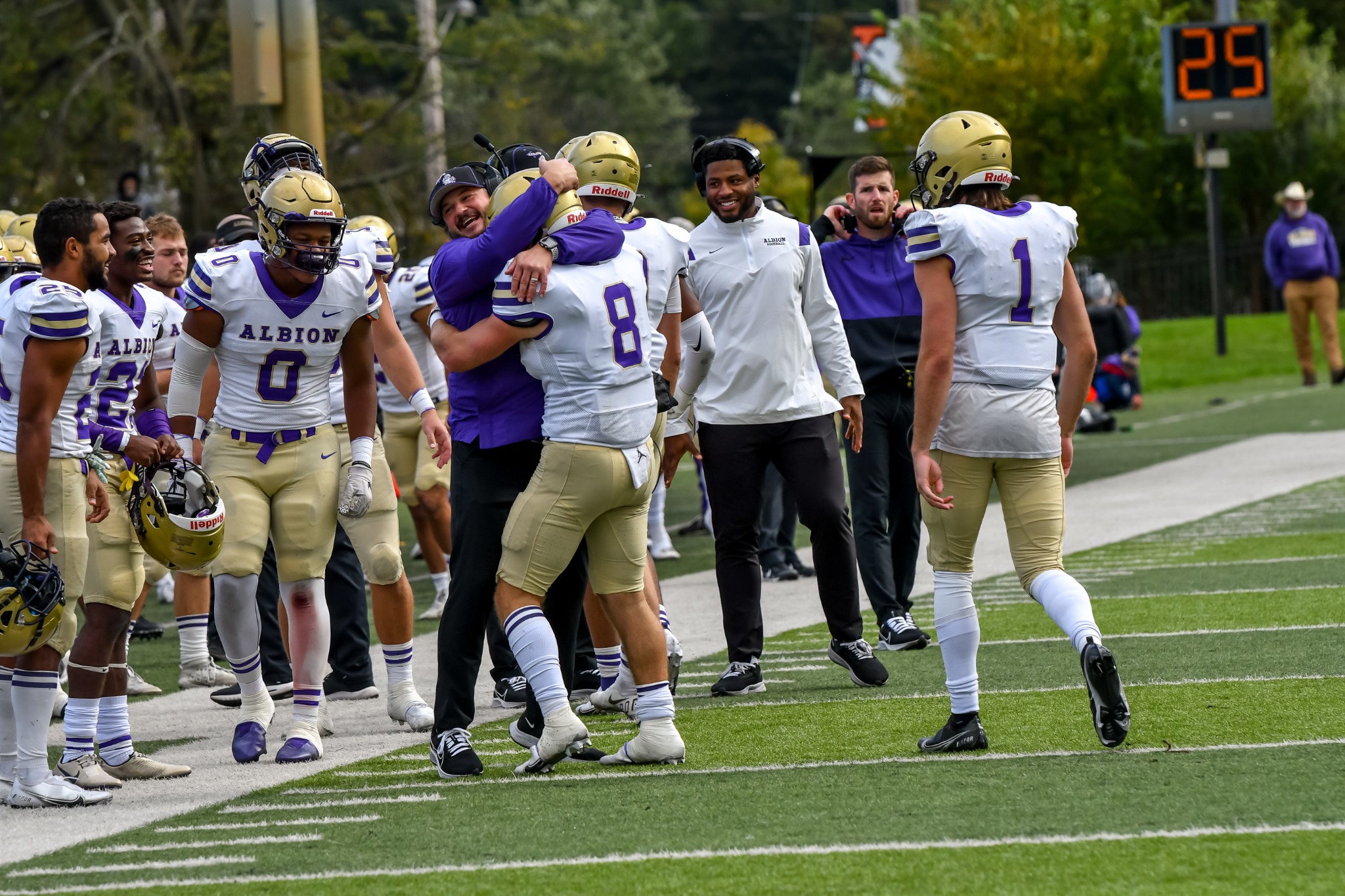 Albion football players and coaches celebrating together on the sideline